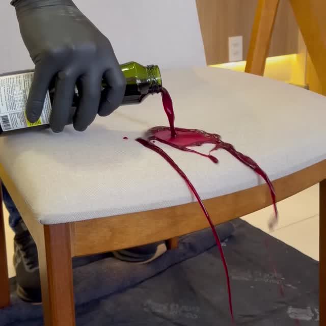 Técnico da Doutor Sofá, de máscara, óculos, luvas e proteção nos pés, limpando as almofadas de um sofá claro.